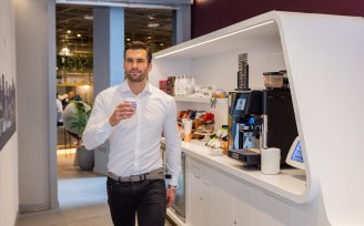 Man with coffee walking past Grab + Go